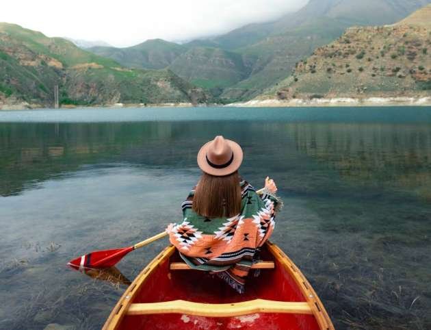 Girl canoeing on a lake in the mountains on a cloudy day. Moody atmosphere on Lake Gizhgit in the village of Bylym, Kabardino-Balkaria